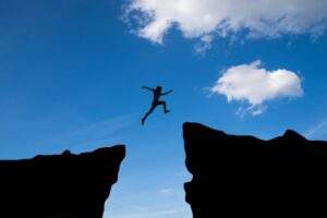 Imagen de persona saltando de una montaña a otra. Cuáles son las principales causas del fracaso